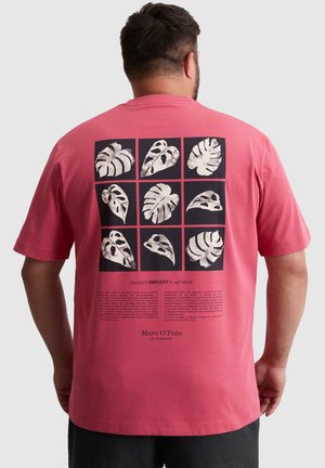 Roze katoenen t-shirt met een achterprint van zwart-witte bladillustraties in een rasterlayout, met tekst die conserveringsthema's benadrukt.