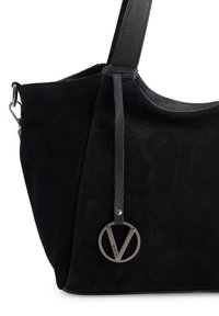 Zwarte suède handtas met leren accenten en een ronde metallic logo charm. Heeft een gestructureerde strap en een zachte, gestructureerde vorm.