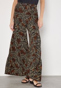 Wide-leg pants in a black fabric featuring a multicolored leaf pattern with shades of orange and gold. Elastic waist and flowy design.