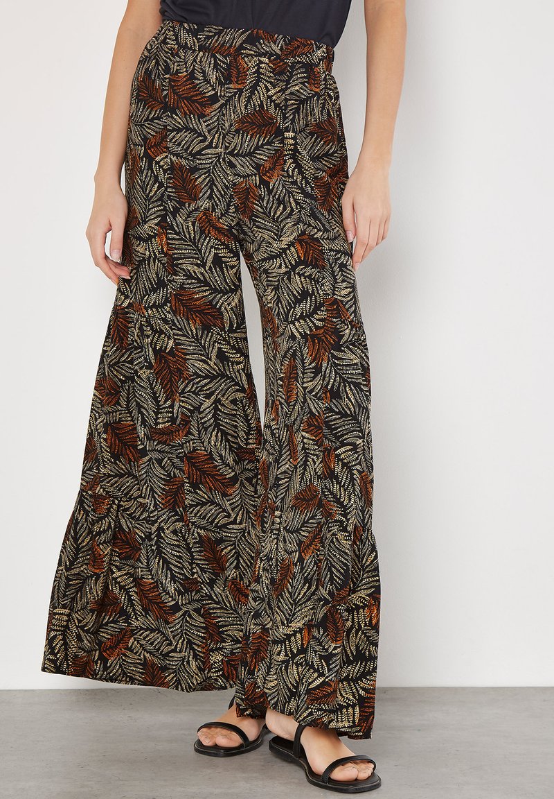 Wide-leg pants in a black fabric featuring a multicolored leaf pattern with shades of orange and gold. Elastic waist and flowy design.
