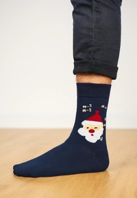 Marineblaue Socken mit einem Weihnachtsmann-Design, der einen roten Hut und einen weißen Bart trägt, gefertigt aus weichem Stoff mit glatter Textur.
