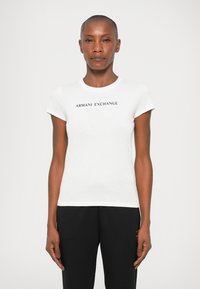 Bela bomba iz bombaža z okroglim izrezom in kratkimi rokavi, s črnim tiskanjem "ARMANI EXCHANGE" čez prsi.