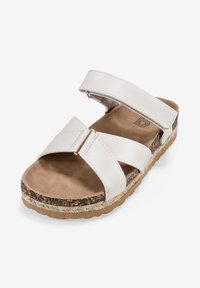 Sandal bianca a due cinghie con una soletta morbida e testurizzata e un sottopiede in sughero. Presenta parti metalliche in tonalità oro e una suola piatta in gomma.