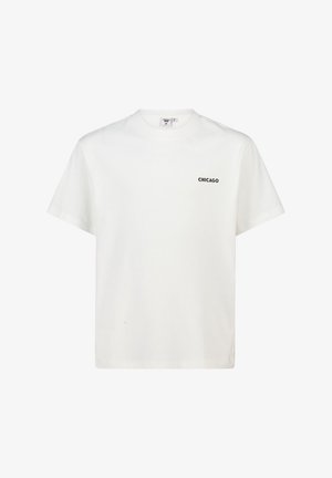 Camiseta blanca de manga corta con cuello redondo y la palabra "CHICAGO" impresa en texto negro pequeño en el lado izquierdo del pecho.