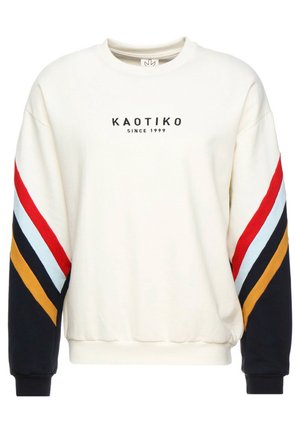 Witte crewneck trui met KAOTIKO-logo en de tekst "Since 1999", met rode, lichtblauwe, zwarte en mosterdkleurige strepen op de mouwen.
