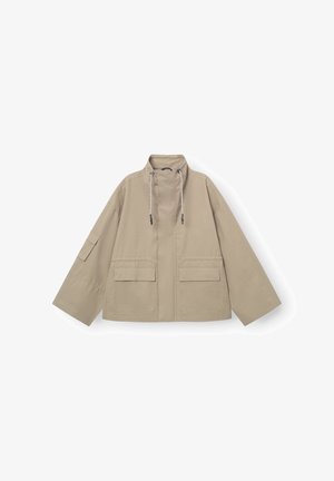Beige functionele jas met een hoge kraag, twee zakken aan de voorkant en verstelbare trekkoorden bij de nek. Heeft wijde mouwen en een ontspannen pasvorm.