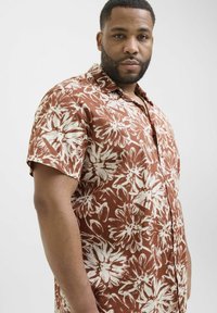 Lühikeste varrukatega särk pruunide ja valgete lillemustritega, kergetest kangast, nööpidega ees ja kraega.