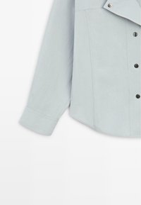 Camicia azzurro chiaro con colletto, maniche lunghe e bottoni neri sul davanti. Il materiale sembra liscio con una texture sottile.