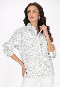 Koszula w leopardzie wzory w odcieniach szarości, zapinana na guziki, z kołnierzykiem, podwiniętymi rękawami, dwoma przednimi kieszeniami oraz miękkim, teksturowanym materiałem.