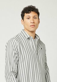 Camicia a righe grigia e bianca, con colletto a punta e bottoni frontali. Realizzata in tessuto leggero con una vestibilità slim.