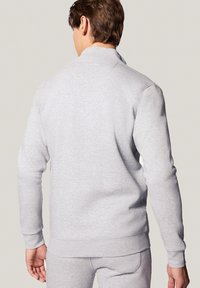 Jasnoszara bluza z kołnierzykiem, długimi rękawami i ściągaczami u dołu. Miękka tkanina o gładkiej fakturze, prezentująca minimalistyczny design.