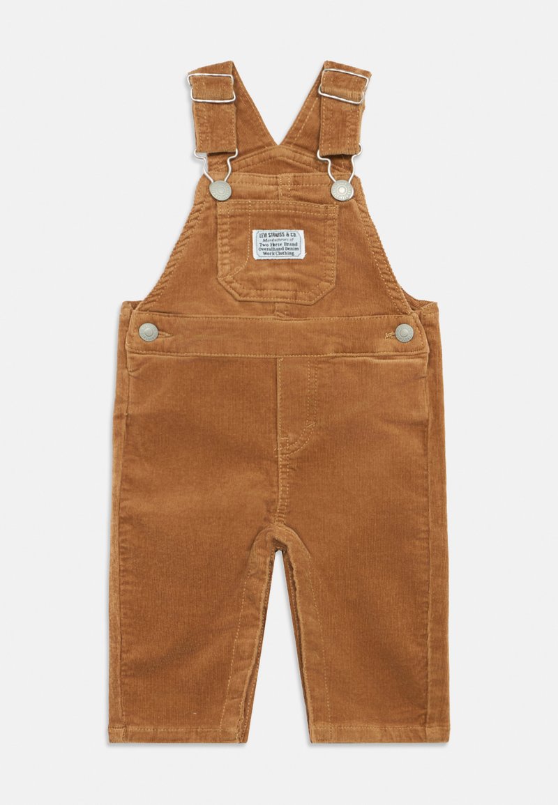 Jardineiras de corduroy castanho com alças ajustáveis, fechos metálicos, bolso frontal e etiqueta da marca. Textura suave com riscas verticais.