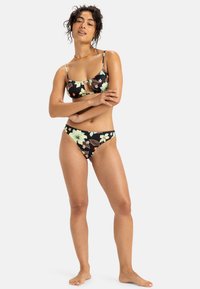 Zwart bloemenbikiniset met een bralette-top met verstelbare bandjes en een sleufdetail, gecombineerd met laagversneden bikinibroekjes.