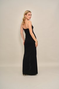 Juoda vakarinė suknelė su prigludusiu siluetu, papuošta perlų detalėmis ant petnešėlių, elegantiška forma ir subtilia šonine skeltuke judesiui.
