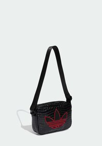 Črna torbica z reliefom krokodilske kože z zadrgo in rdečim izvezenim logotipom. Vključuje tanek črn trak za nošenje.