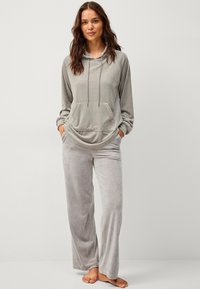 Ensemble de lounge en velours gris clair comprenant un haut à capuche avec une poche avant et un pantalon large assorti et doux. Texture lisse, coupe décontractée.