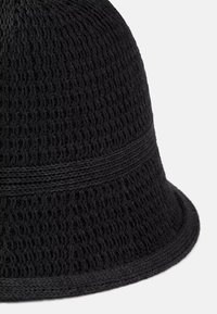 Czarna dzianinowa kapelusz bucket z teksturowanym wzorem, z gładkim paskiem wokół korony i dopasowanym dolnym krawędzią.