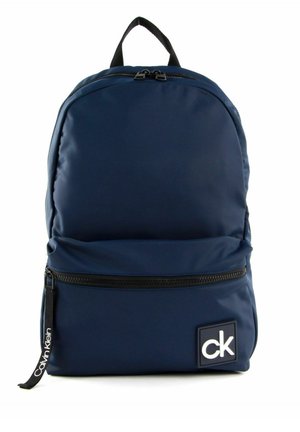 Sac à dos bleu marine Calvin Klein avec fermeture éclair noire, poignée supérieure, poche avant et écusson logo blanc "ck" en bas à droite à l'avant.