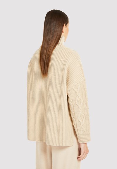 Suéter de punto beige con cuerpo acanalado y mangas de punto trenzado, con un cuello alto y un corte suelto y relajado.