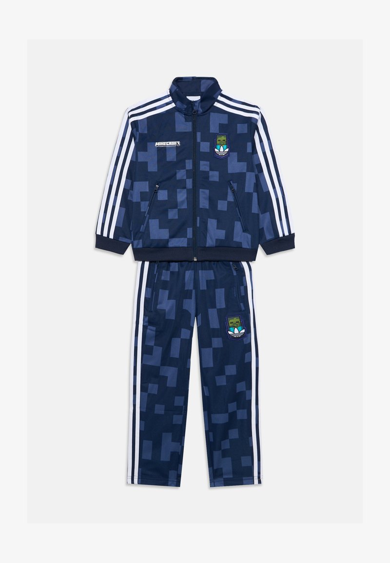 Haditengerészeti tréningruha pixelmintával, zipzáros dzseki, fehér csíkok az ujjakon és a nadrágon, a Minecraft és az Adidas logóival.