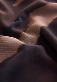 Tessuto a rete in tonalità marroni e crema con un motivo testurizzato, che mostra un aspetto morbido e ondulato e sottili variazioni di colore.