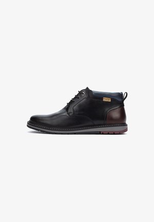 Zwarte leren enkelboots met een suede kraag, grijze zool en bruine hakaccenten. Voorzien van zes oogjes voor veters en logo-detail.