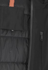 Interno di giacca nera trapuntata con tasca con zip sulla destra e un'asola di tessuto con etichetta della taglia 50 in alto a sinistra.