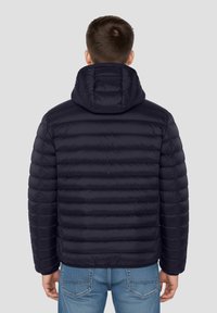 Doudoune bleu marine avec capuche, présentant un design matelassé horizontal et des poignets élastiques. Texture lisse avec une coupe ajustée.