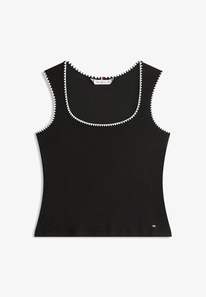 Schwarzes ärmelloses Tanktop mit weißem Zickzackbesatz entlang des Halsausschnitts und der Armlöcher, kleines Tommy Hilfiger-Logo nahe dem unteren Saum.