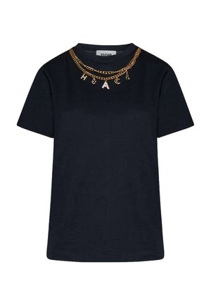 Maglietta nera a maniche corte con due collane a catena dorate che presentano ciondoli a lettere che formano la parola "HACK" intorno al colletto.