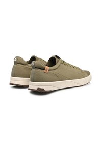 Un par de zapatillas bajas color verde oliva con suelas blancas, hechas de tela de malla, con tiradores y etiqueta de la marca en el talón y la suela.