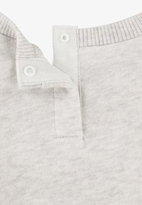 Chemise en coton gris clair avec un col côtelé, présentant une patte de boutonnage et une texture douce, affichant un motif chiné subtil.
