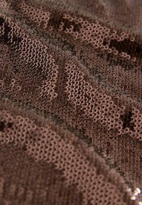 Braunes Paillettenmaterial mit strukturiertem Oberfläche, das überlappende kreisförmige Pailletten aufweist, die das Licht reflektieren und einen schimmernden Effekt erzeugen.