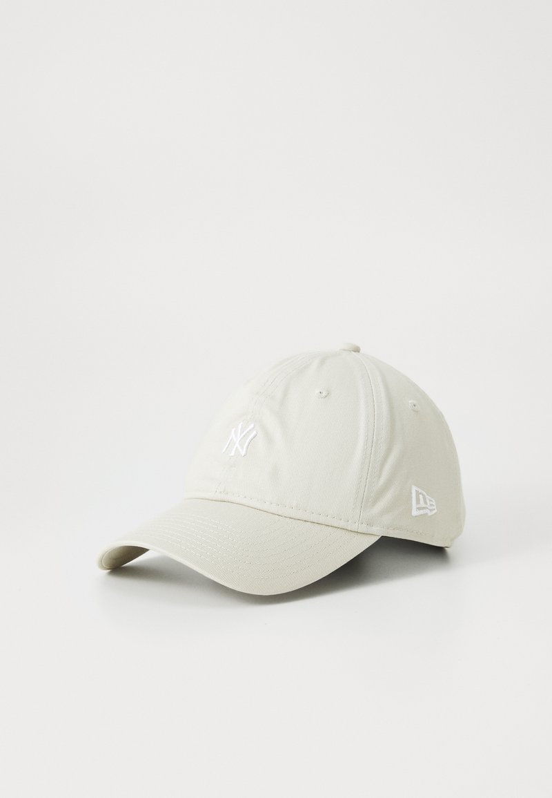 Beige baseball cap with curved brim, featuring white embroidered New York Yankees logo on front and New Era logo on side.