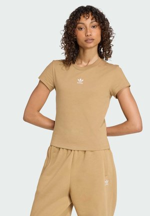 Hellbraunes, tailliertes T-Shirt aus Baumwolle mit kurzen Ärmeln und rundem Ausschnitt; verfügt über ein kleines weißes Adidas-Logo auf der Brust.