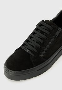 Sneaker din suede negru, cu șireturi plate negre, fermoar lateral, talpă din cauciuc texturat și un design minimalist fără logo-uri vizibile.