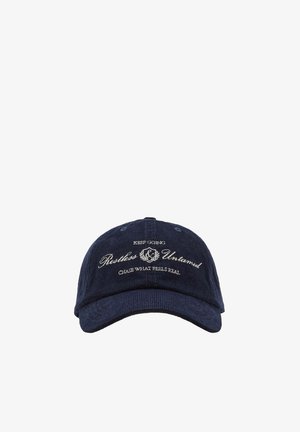 Marineblå kordfløjls baseballkasket med hvidt broderet tekst "Keep Going Restless & Untamed Chase What Feels Real" på fronten.