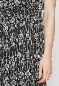 Rochie cu un model alb-negru, prezentând un design floral, talie strânsă și un material fluid cu o textură ușoară.