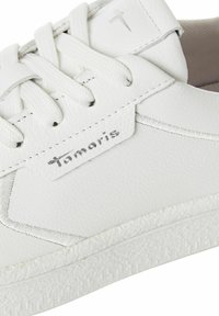 Vit sneakers tillverkade av syntetiskt material. Utrustade med platta snören, en texturerad gummisula och en silverfärgad logotagg på sidan.