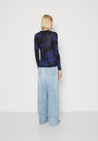 Maglietta a maniche lunghe di colore blu scuro con un motivo tie-dye, abbinata a jeans a gamba larga di colore blu chiaro, con una vestibilità comoda e tasche posteriori.