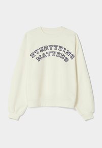 Krémově zbarvená mikina s kulatým výstřihem, širokými rukávy a zakřiveným textovým motivem „EVERYTHING MATTERS“ v námořnicky modré výšivce.