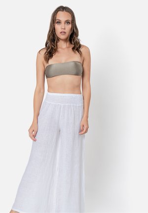 Top bandeau beige abbinato a pantaloni larghi di lino bianchi, caratterizzati da un elastico in vita e una texture leggera e ariosa.