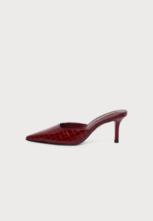 Mule rouge à talon haut avec bout pointu et finition brillante à texture croco sur fond blanc.