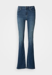 Τζιν καμπάνα σε ξεθωριασμένο μπλε denim, με τσέπες μπροστά, ψηλή μέση και φθαρμένες λεπτομέρειες με ορατές ραφές.