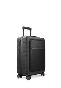 Valise noire rigide avec une poignée télescopique, quatre roues, poche zippée à l'avant et accents horizontaux. Surface texturée avec des rainures.