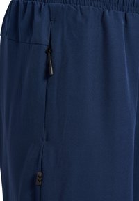 Marina sportbyxor gjorda av ett smidigt tyg, med elastisk midja och justerbar dragsko, samt en liten svart logotypdetalj.