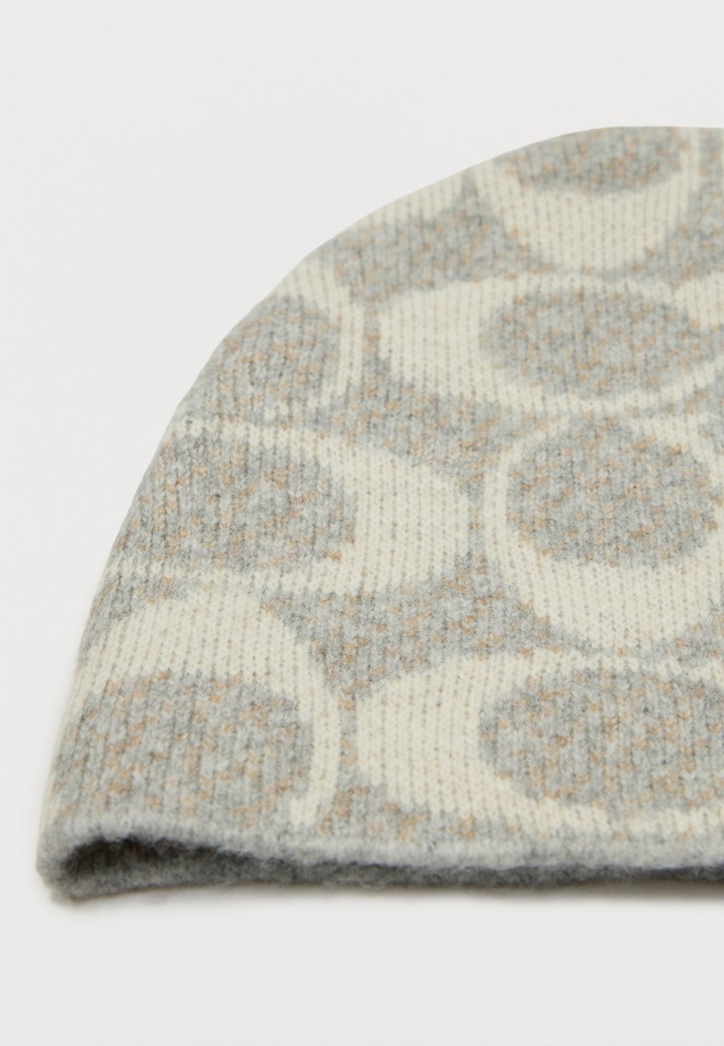 Knit beanie in light gray and cream, featuring a circular pattern, soft texture, and folded edge for warmth.