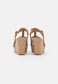 Bruine wedge sandalen met gevlochten jute hak, zachte suède banden en open achterkant. Verstelbare gesp aan de enkel.