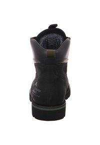 Botín negro de cuero con acabado texturizado, tacón resistente y acento verde en la suela. Cuenta con una lengüeta en la parte posterior para facilitar el calzado.