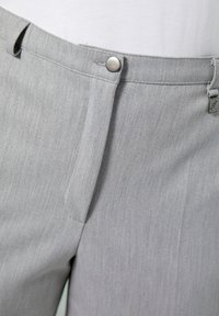 Pantaloni grigi con una texture liscia, dotati di chiusura frontale con bottone, passanti per cintura e una piccola etichetta sulla vita.
